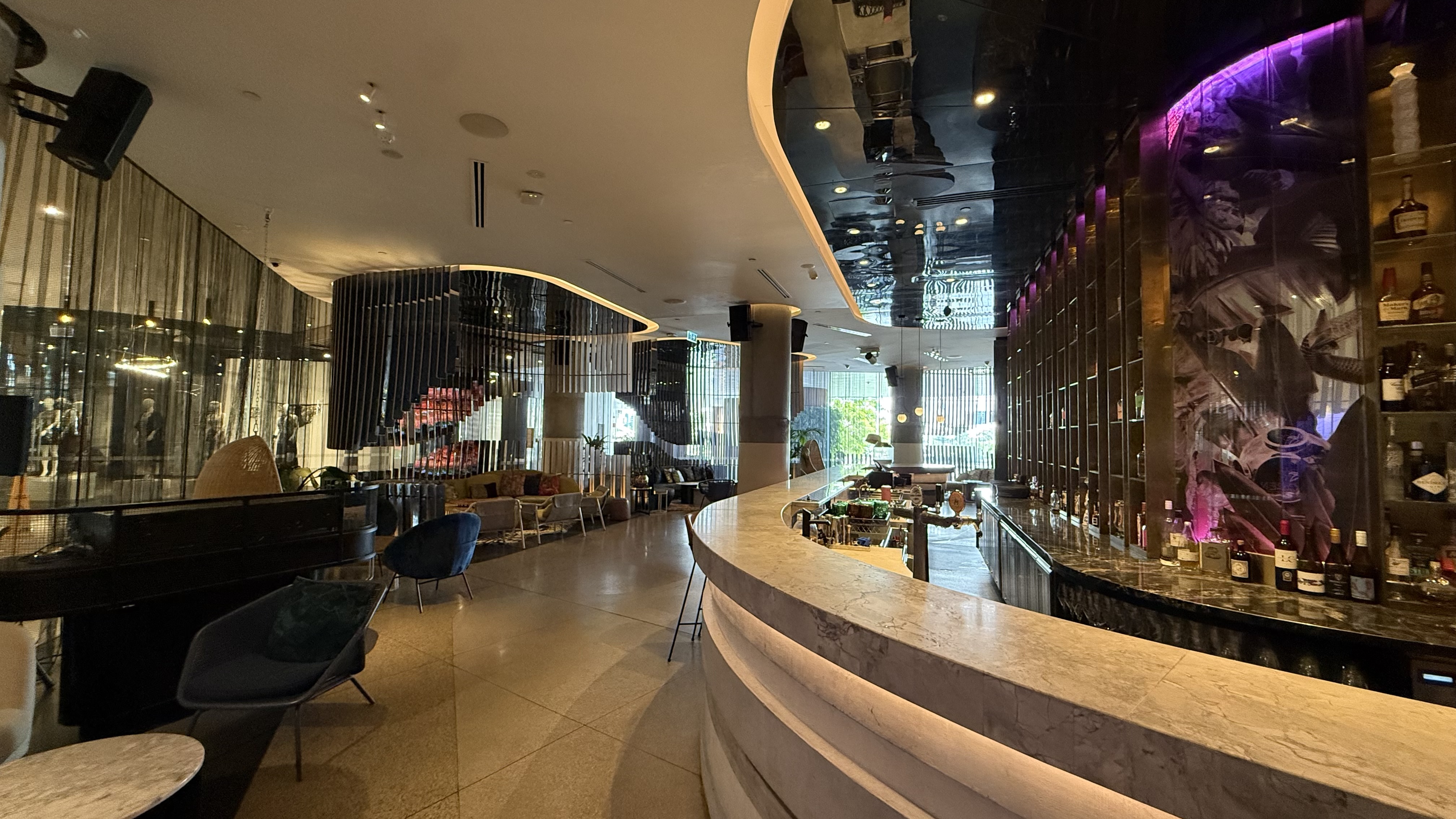 Living Room Bar — curved marble bar, backlit spirits display and dramatic mural wall