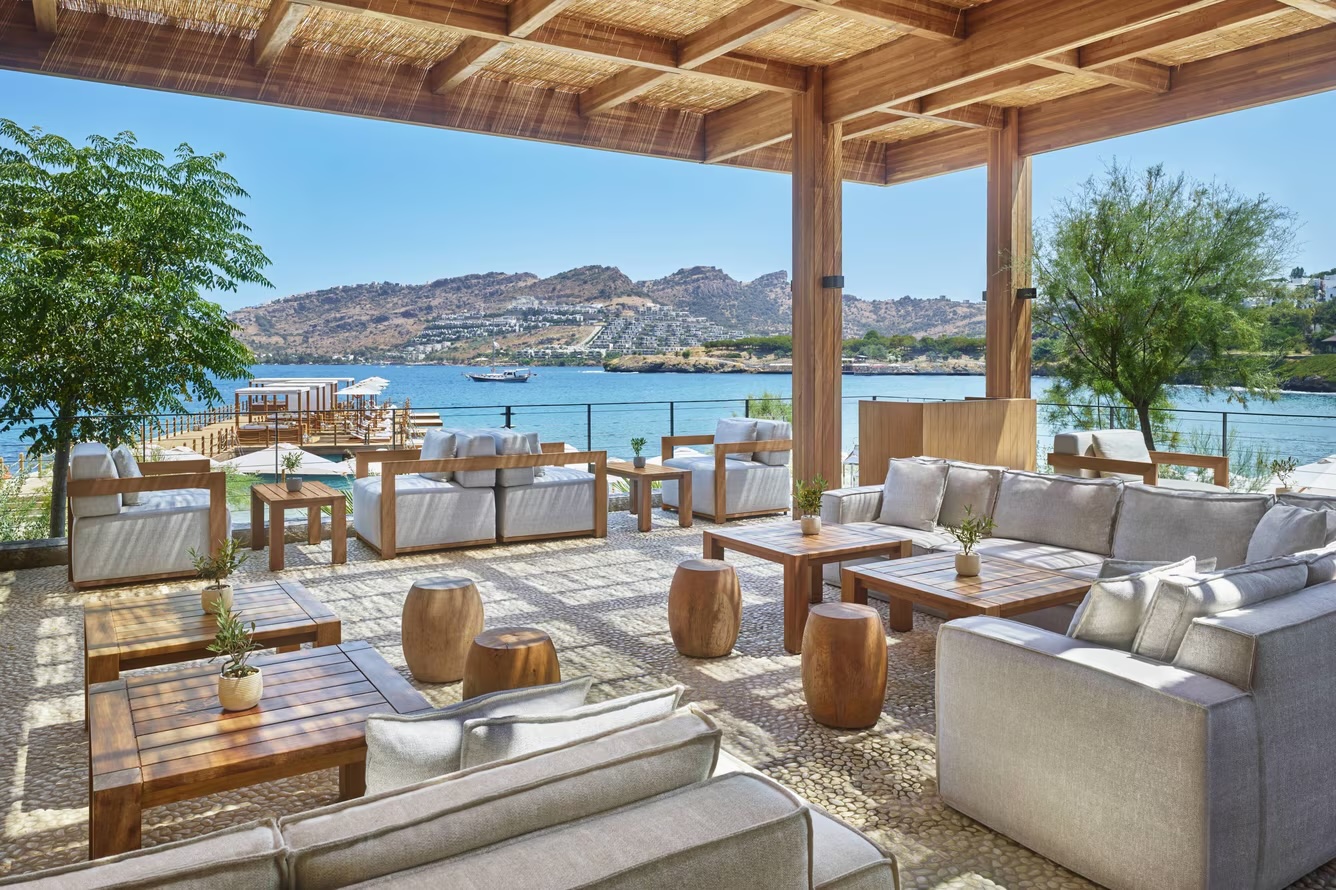 Beach bar and club — teak decking, planting, and the Aegean stretching beyond