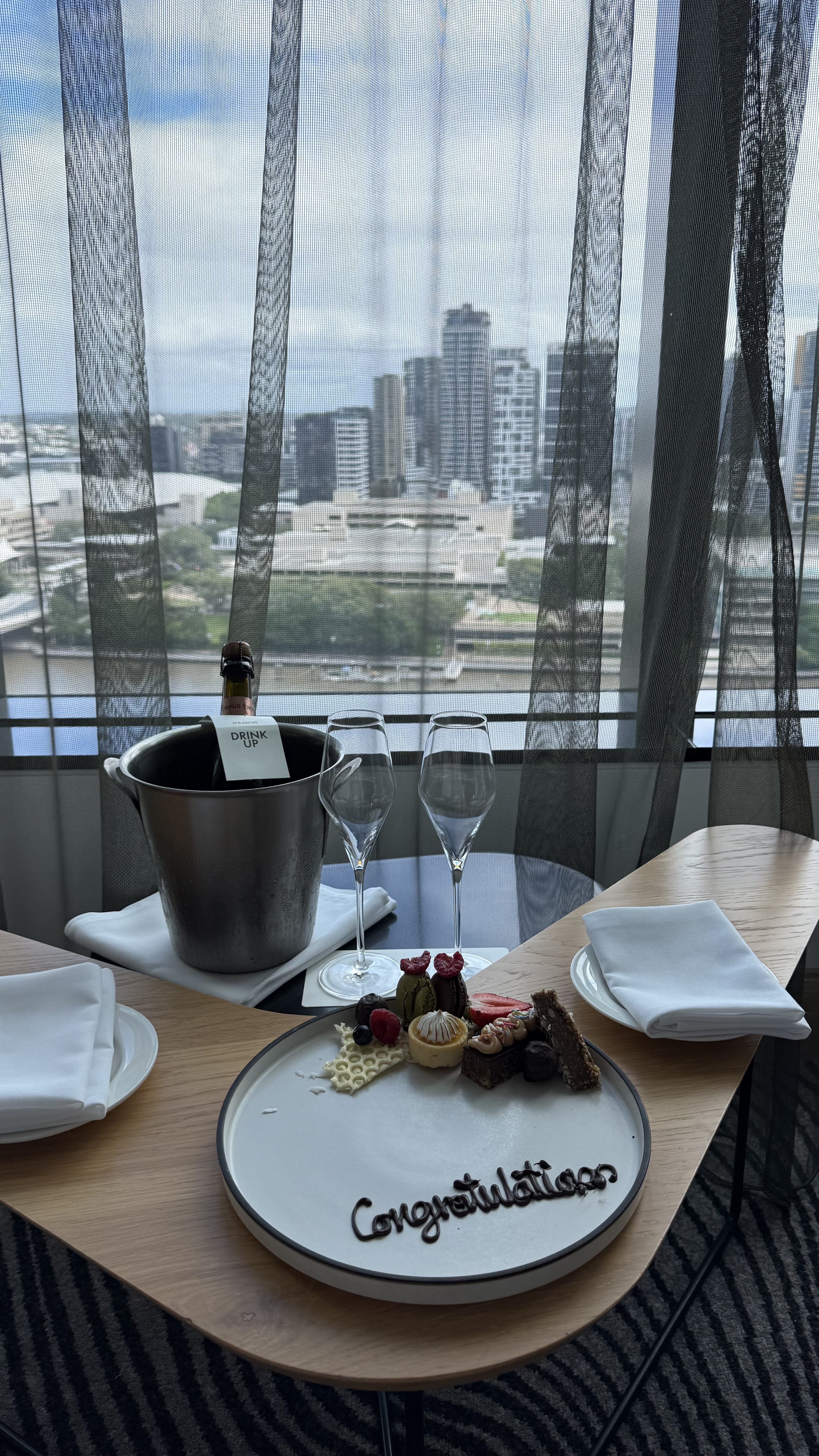 Welcome amenity — champagne on ice, petits fours and Brisbane River views through the sheer curtains