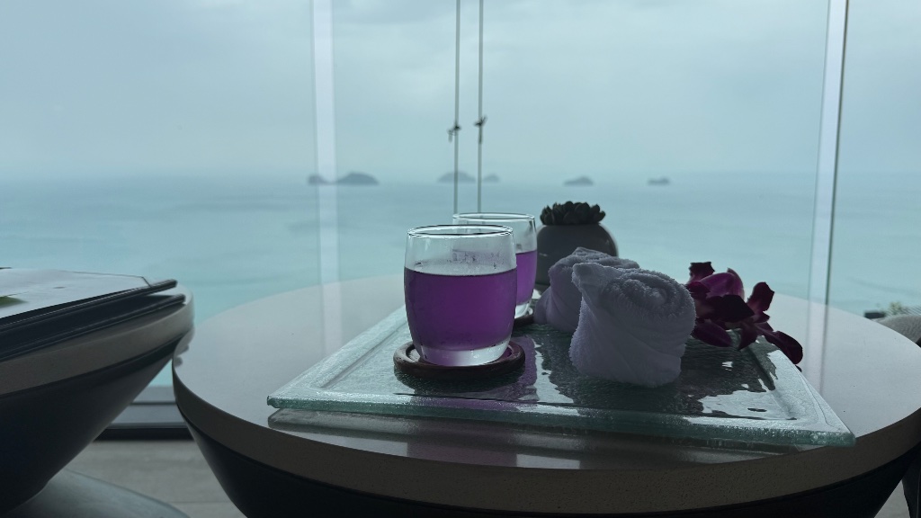 Welcome amenities at arrival - butterfly pea flower drink and cold towels, view of the five islands visible beyond