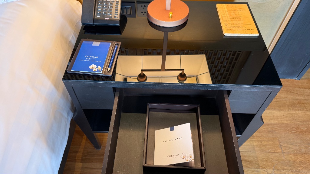 Bedside - pillow menu in the drawer, Conrad notepad and in-villa dining QR