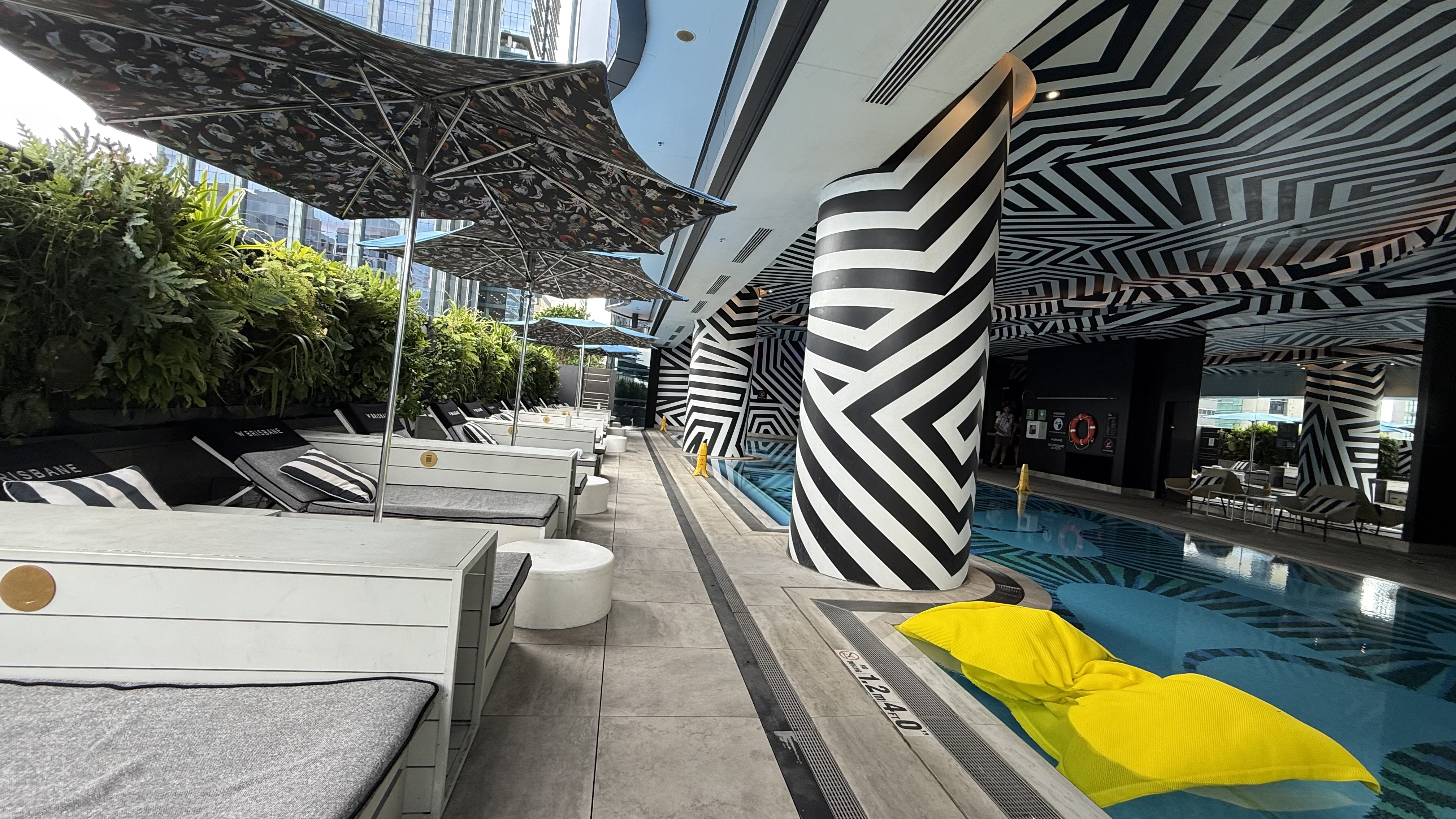 WET Deck — loungers, B&W columns and yellow float beside the pool