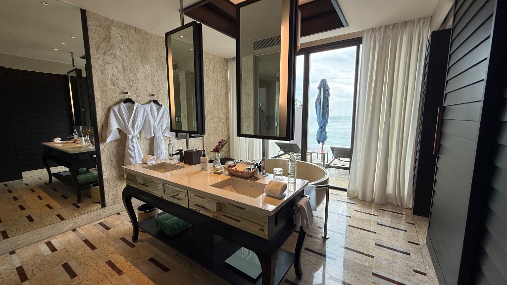 The full bathroom - double vanity with sea view, bathtub and open shower beyond