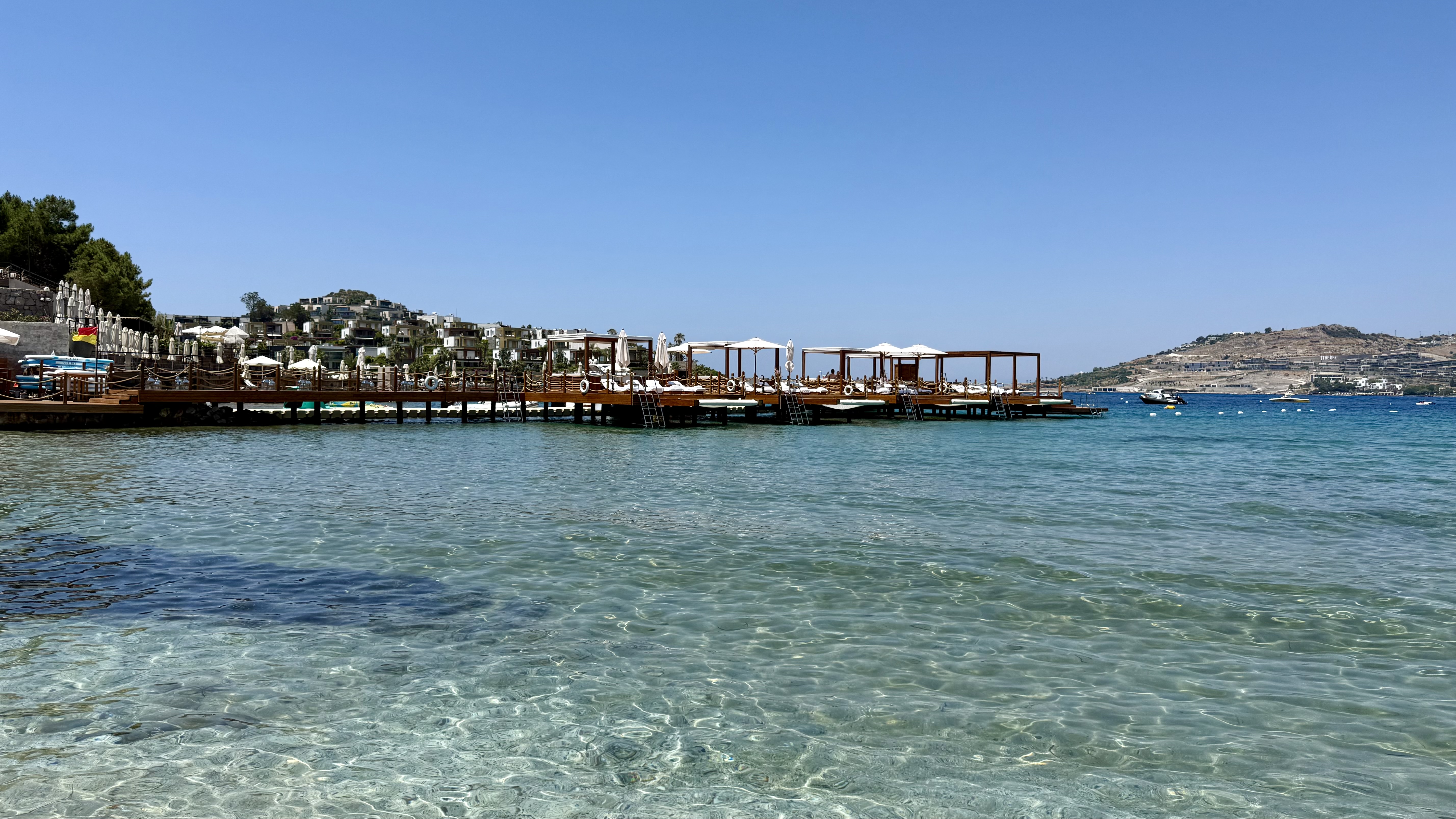 The overwater cabanas and beach club from the water — the full sweep of the bay