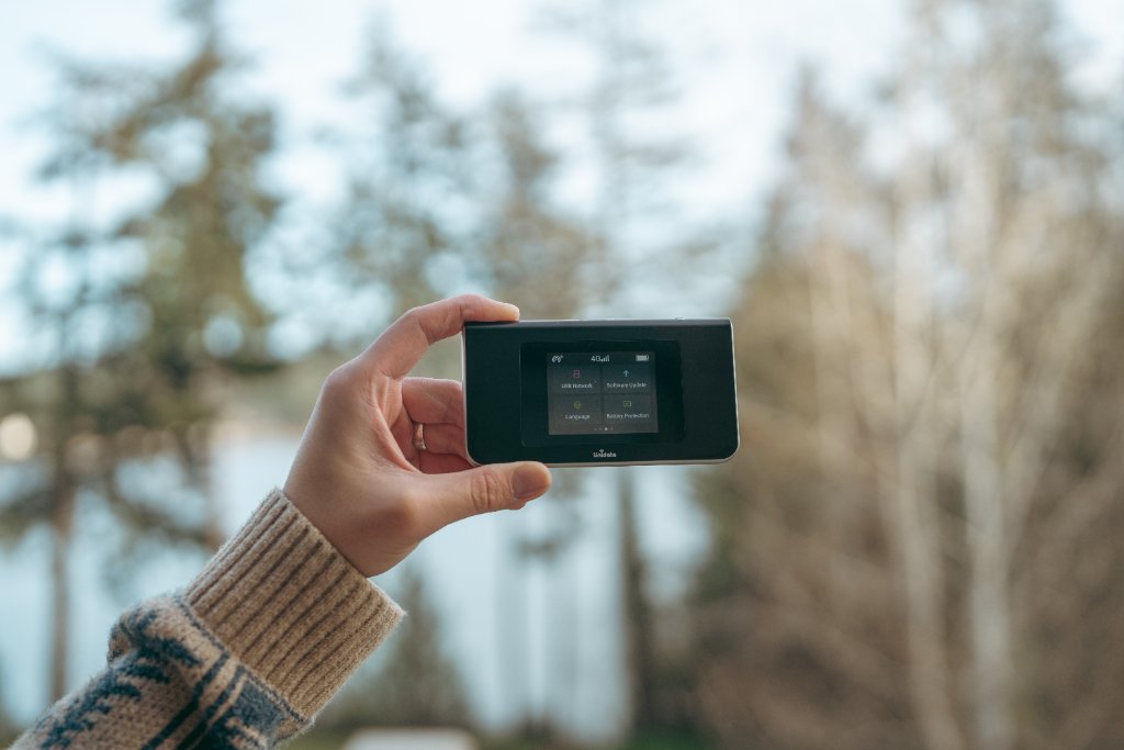 Travel WiFi device held up outdoors at a lake