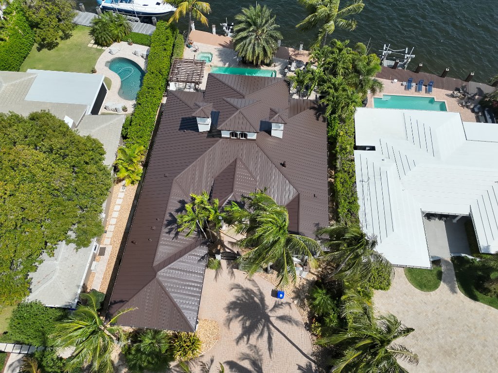 Drone photo of standing seam metal roof on waterfront home in Pompano Beach Florida — Mansard Brown snap lock panels, Intracoastal waterway visible — Coastal Roofing and Waterproofing