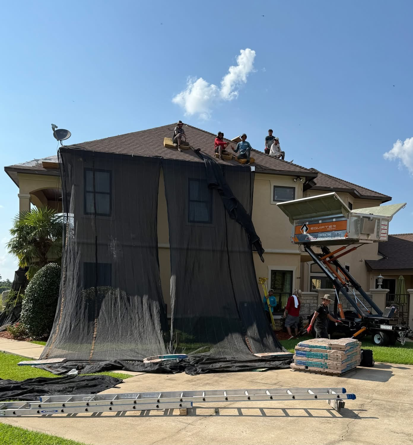 Crew of five shingling a two-story home with Equipter catching debris