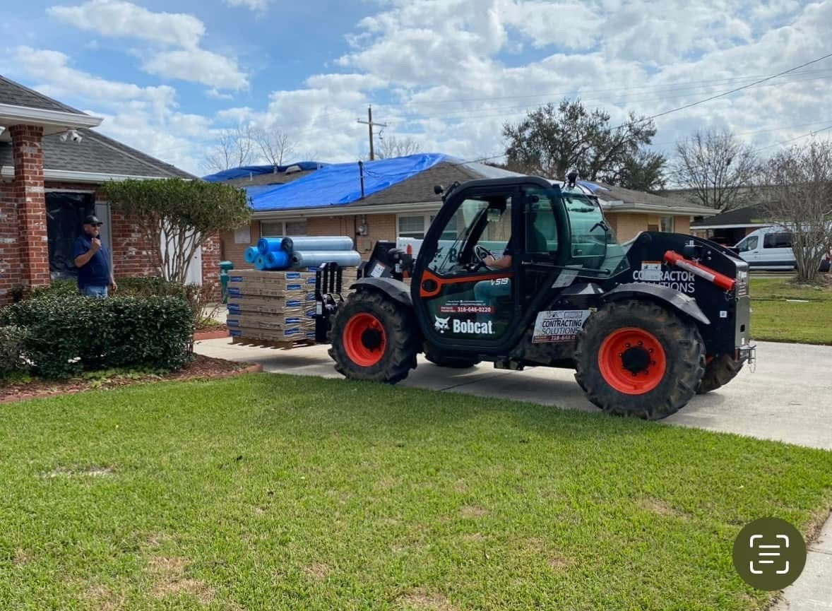 Telehandler staging a pallet of Landmark shingles at the brick home