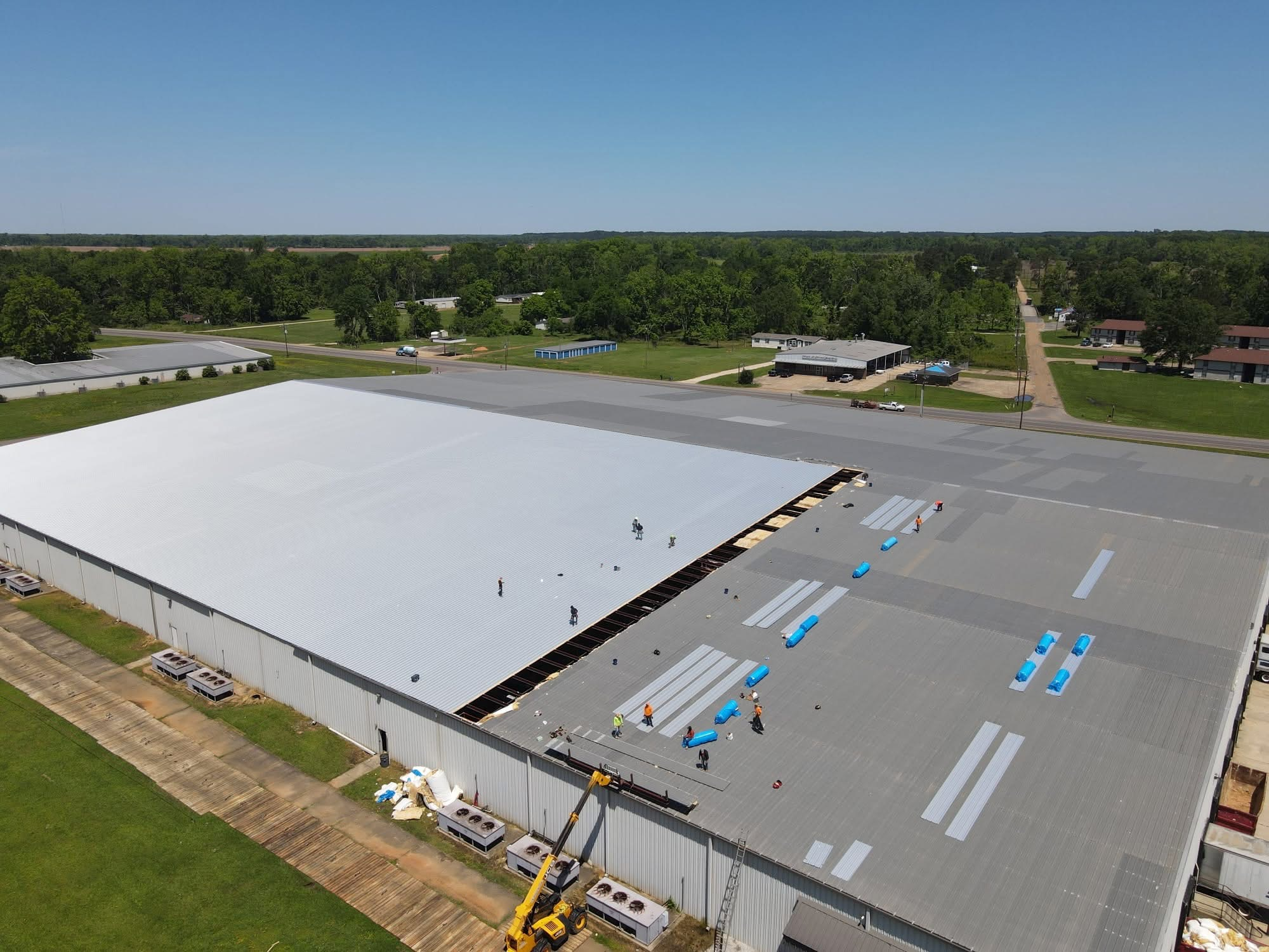 Aerial of commercial warehouse with half the roof stripped to decking