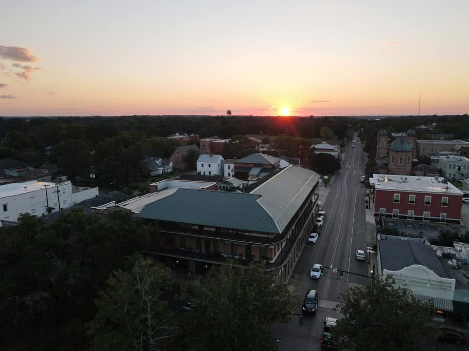 Multi-story commercial building with green metal roof at sunset on a street corner