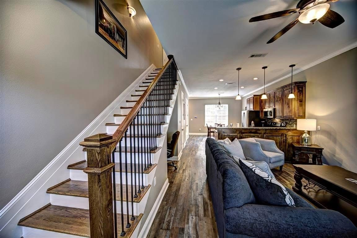 Open-concept interior with dark-stained staircase, wood-look floors and kitchen island