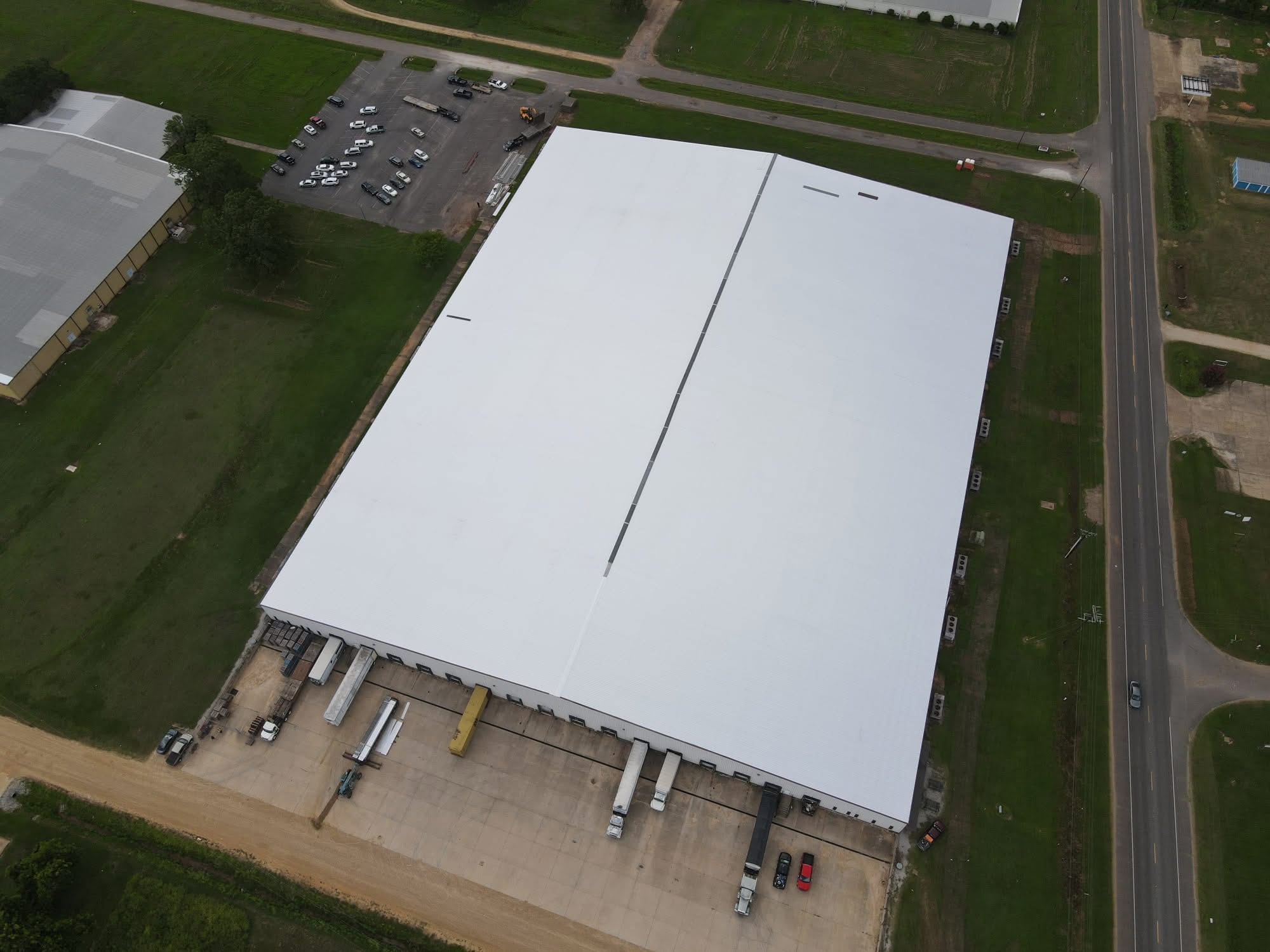 Aerial of commercial warehouse with finished white metal roof and loading dock