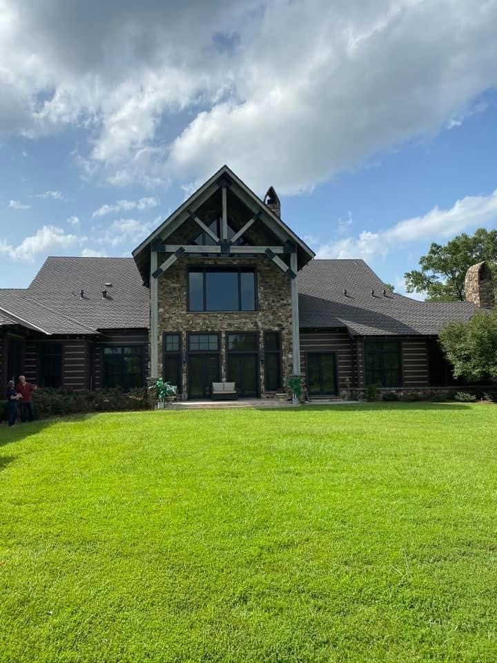 Rustic two-story with stacked-stone and timber-frame gable over the patio
