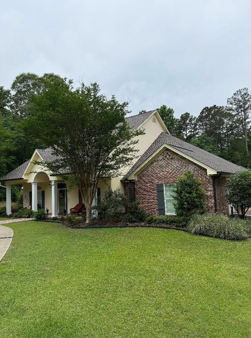 Brick and siding ranch home with dark grey shingle roof and columned entry