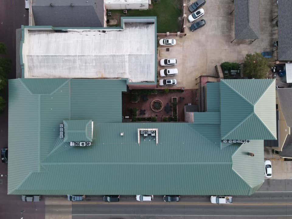Top-down of commercial building with dark green standing-seam roof and brick courtyard