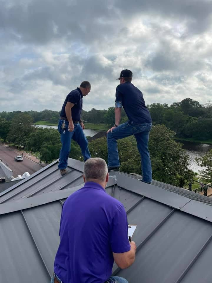 Crew inspecting a grey standing-seam metal roof with clipboards in hand