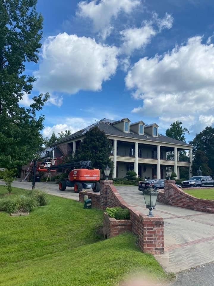 Two-story colonial with orange boom lift accessing the roof for repairs