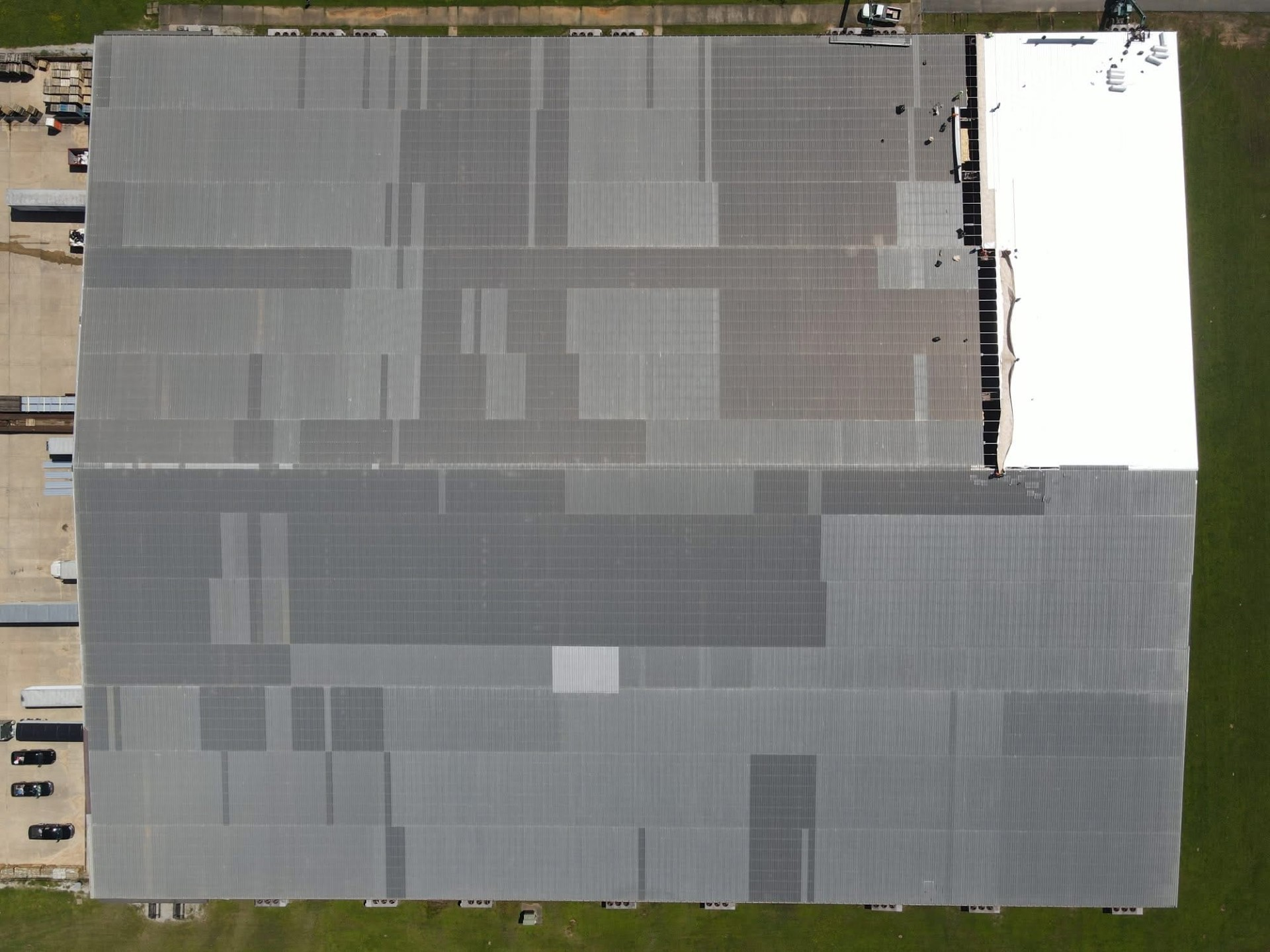 Top-down of commercial metal roof with new white TPO section going in