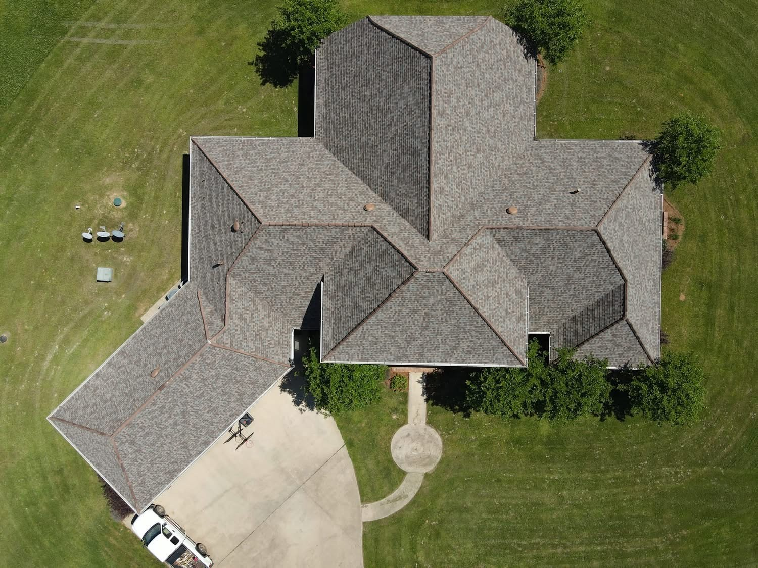 Aerial of single-story home with multi-gabled shingle roof and circular entry walk