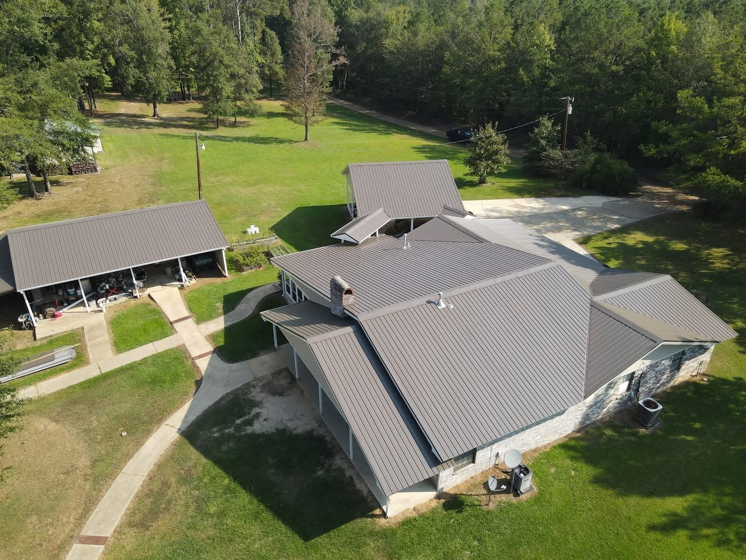 Aerial of finished metal roof with detached garage and stone chimney