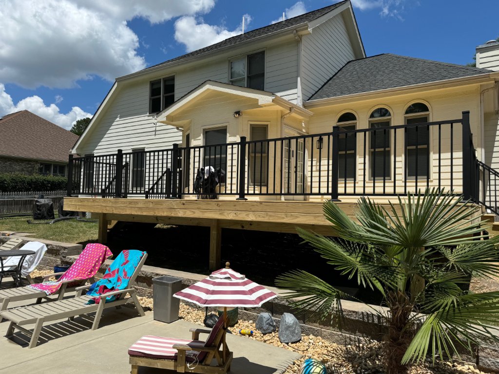 Elevated wood deck with black railing by pool