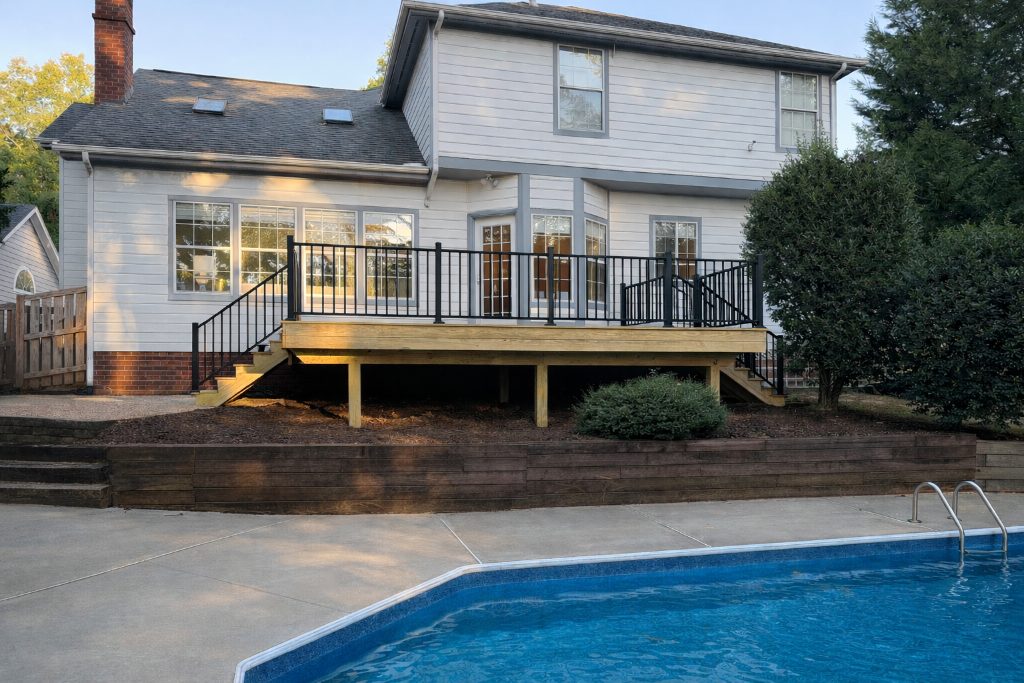 Wood deck with black railing overlooking pool