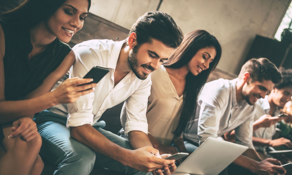 Group of friends smiling and learning together on their phones and laptops