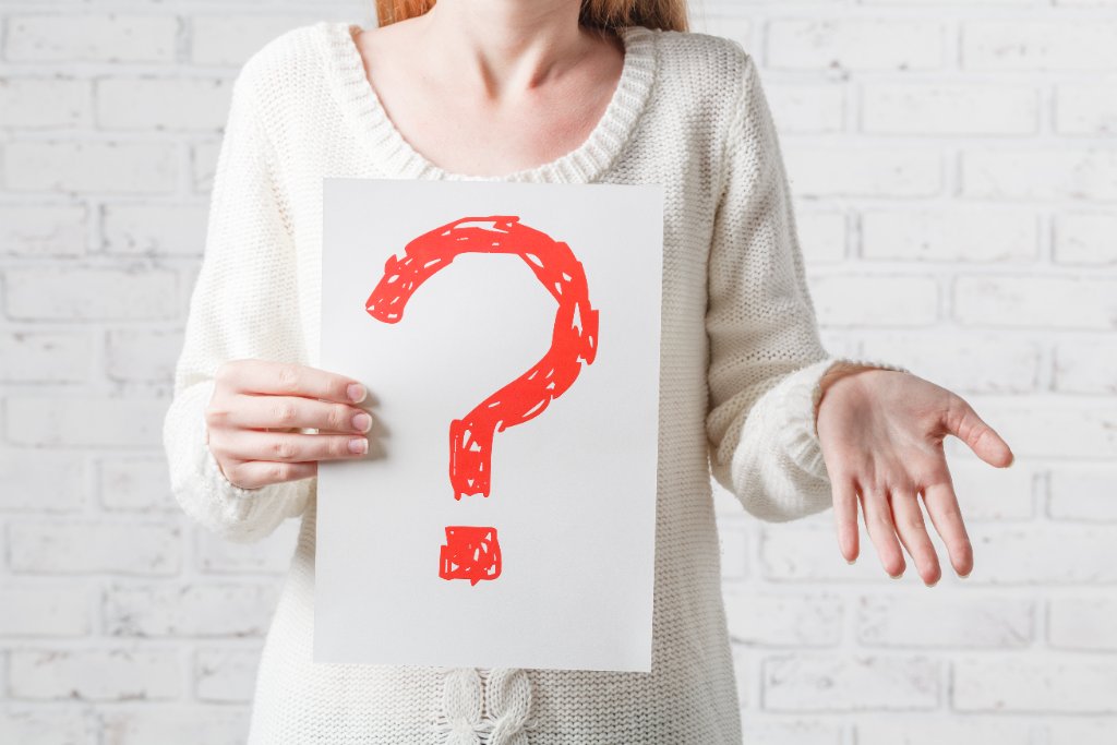 Woman holding a large red question mark, looking for answers about her fertility
