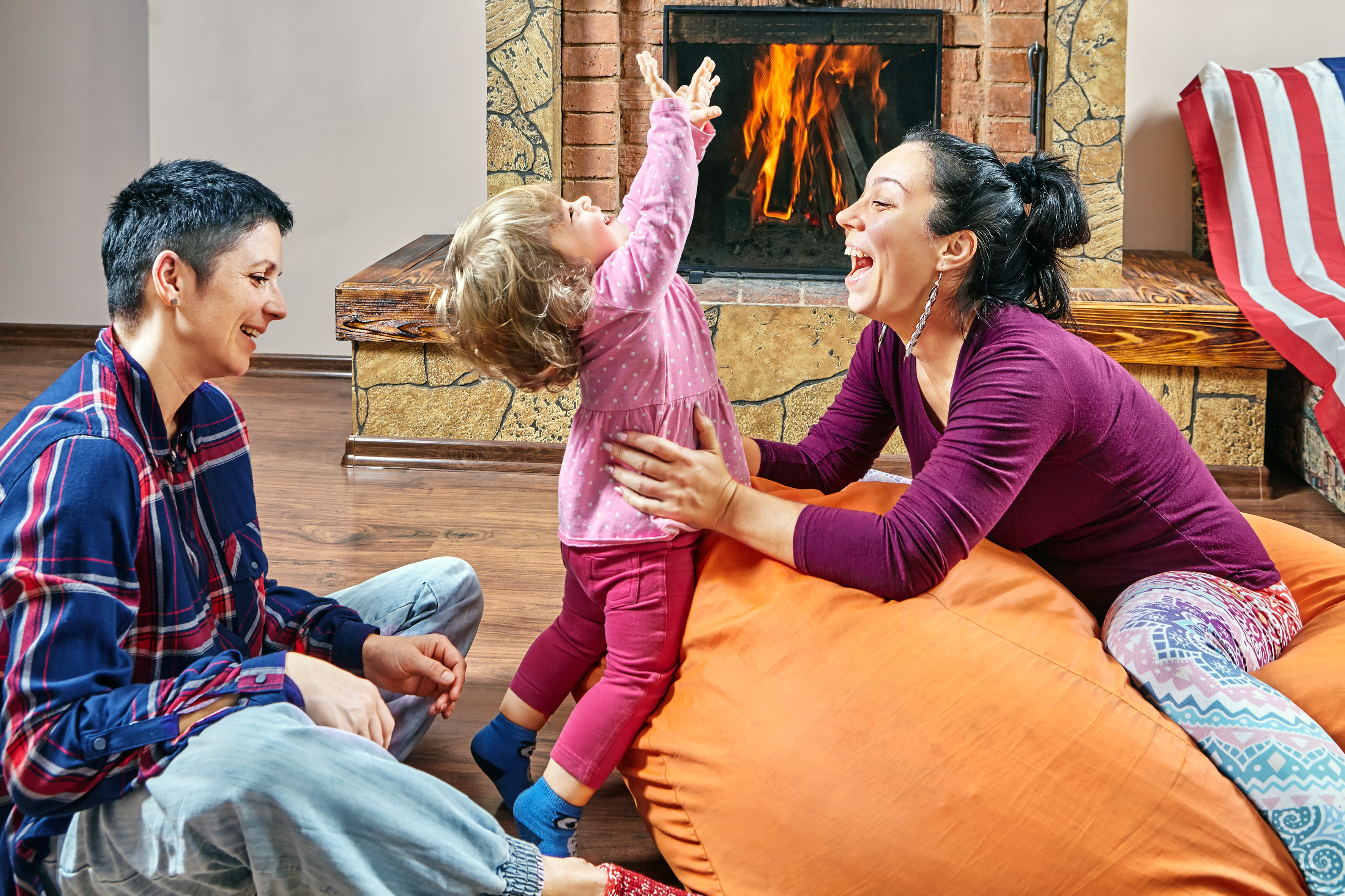 Two mums playing with their child at home after their surrogacy journey