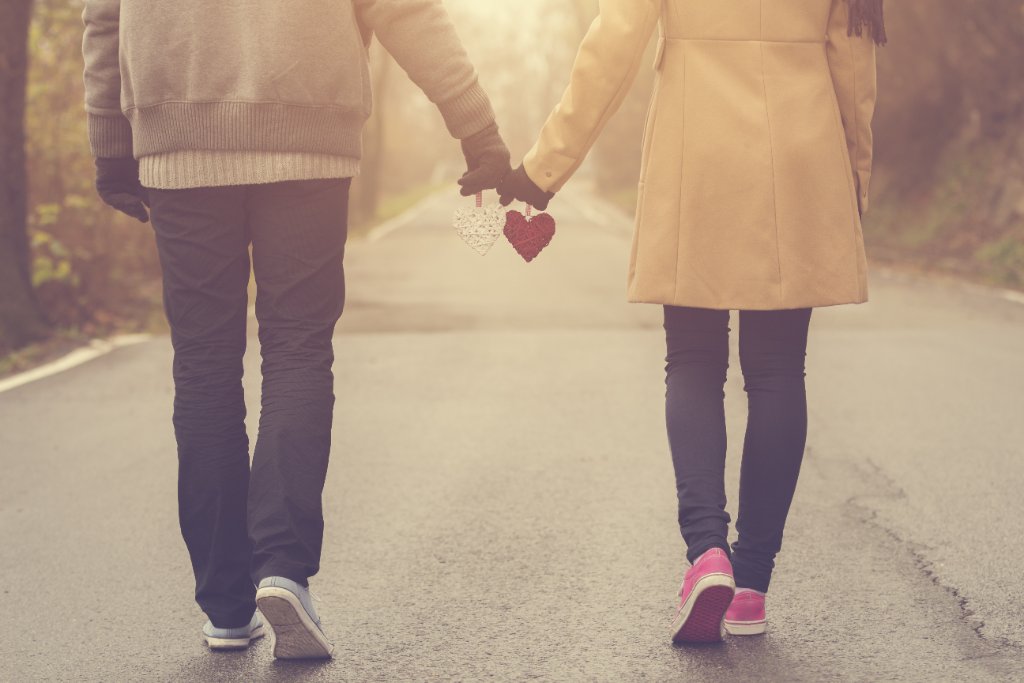 Couple walking together holding hands and two knitted hearts, symbolising hope while trying again after loss