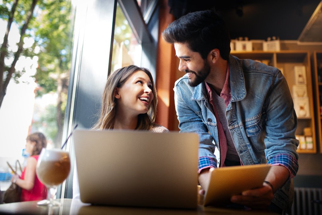 Smiling couple looking at a laptop together in a cafe