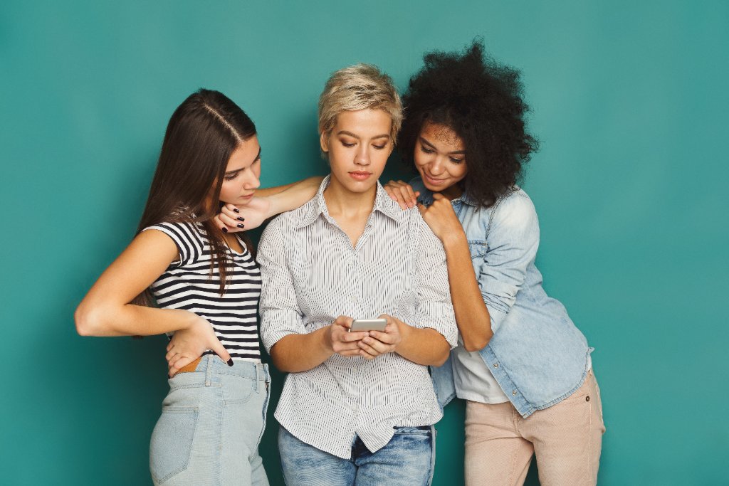 Three young women looking at a phone together considering egg freezing options