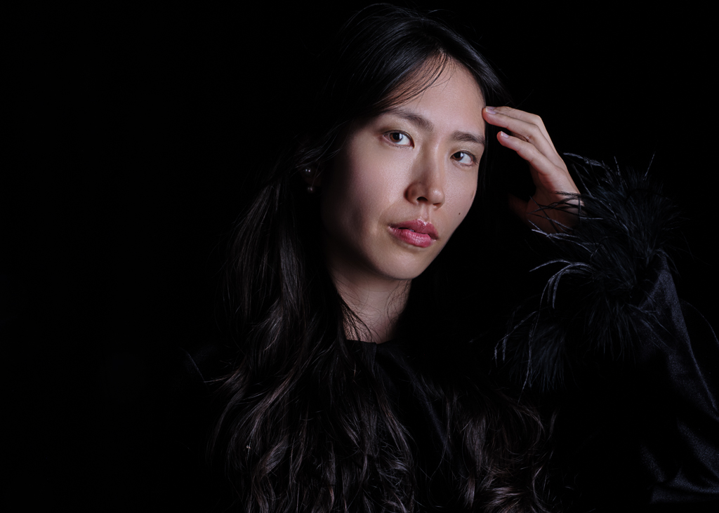 Dramatic portrait with dark background and feathered jacket