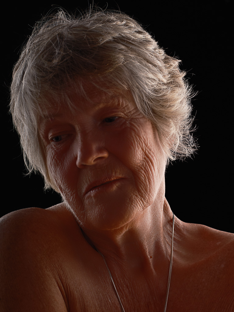 Dramatic portrait of elder woman with silver hair against dark background