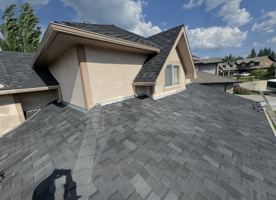 Completed residential roof with gabled dormers and stucco walls