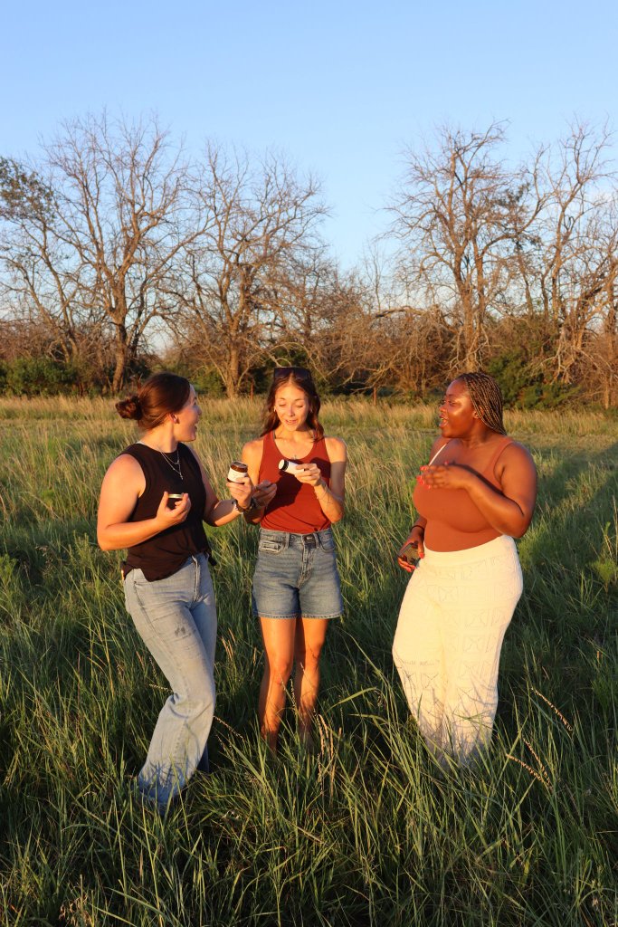 Friends holding Wagyu Wellness products in a field