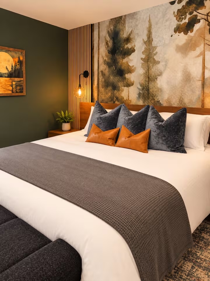 Bedroom with forest mural wallpaper and textured pillows
