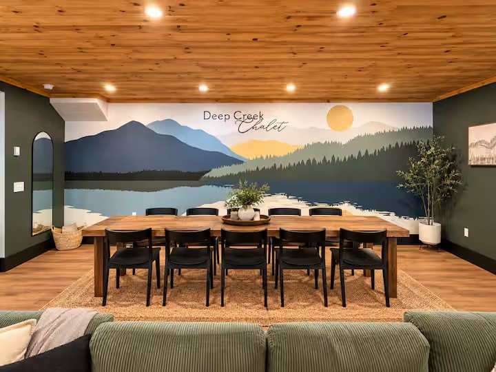 Dining room with long wooden table and mountain landscape mural