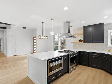 Modern kitchen remodel in Dallas with black cabinets, white quartz island, stainless steel range and pendant lights
