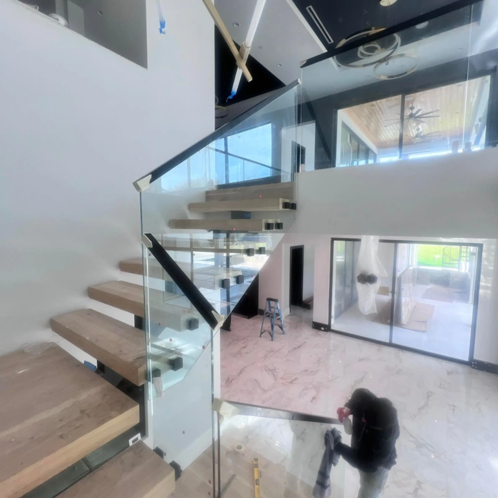 Elegant open-riser floating staircase with glass railing and light wood treads under construction in Dallas Texas by 448 Developments