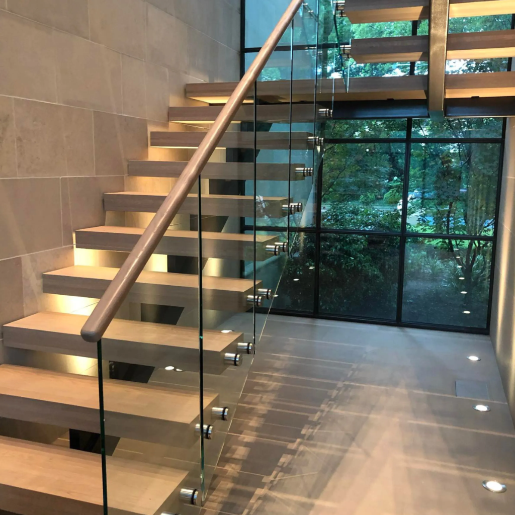 Luxury custom floating staircase with frameless glass panels and black handrail in a grand foyer by 448 Developments DFW