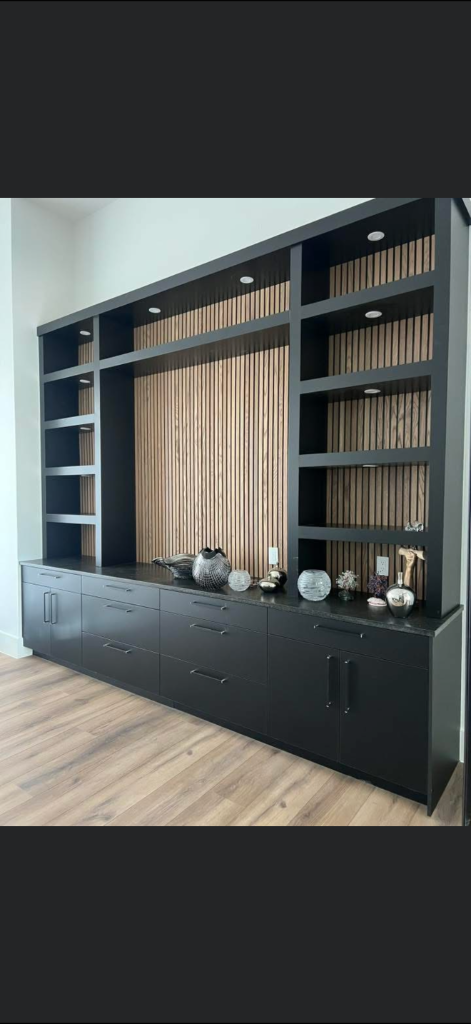 Modern black built-in entertainment wall unit with wood slat accent panel and lower cabinets