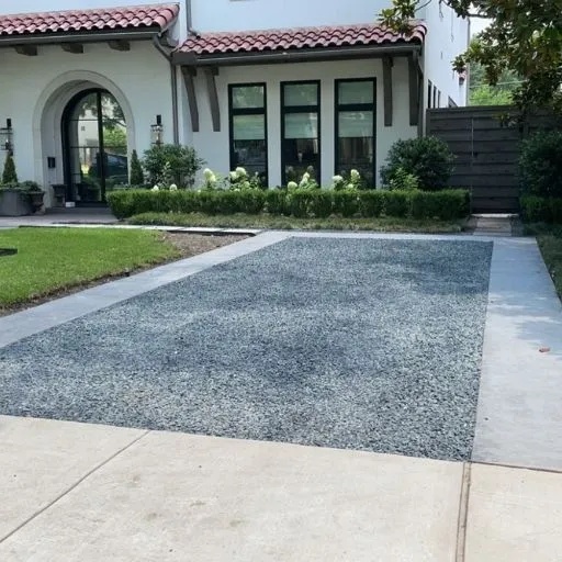 Stylish gravel driveway with clean concrete edging in front of a traditional home in Dallas, offering a unique and low-maintenance driveway solution.