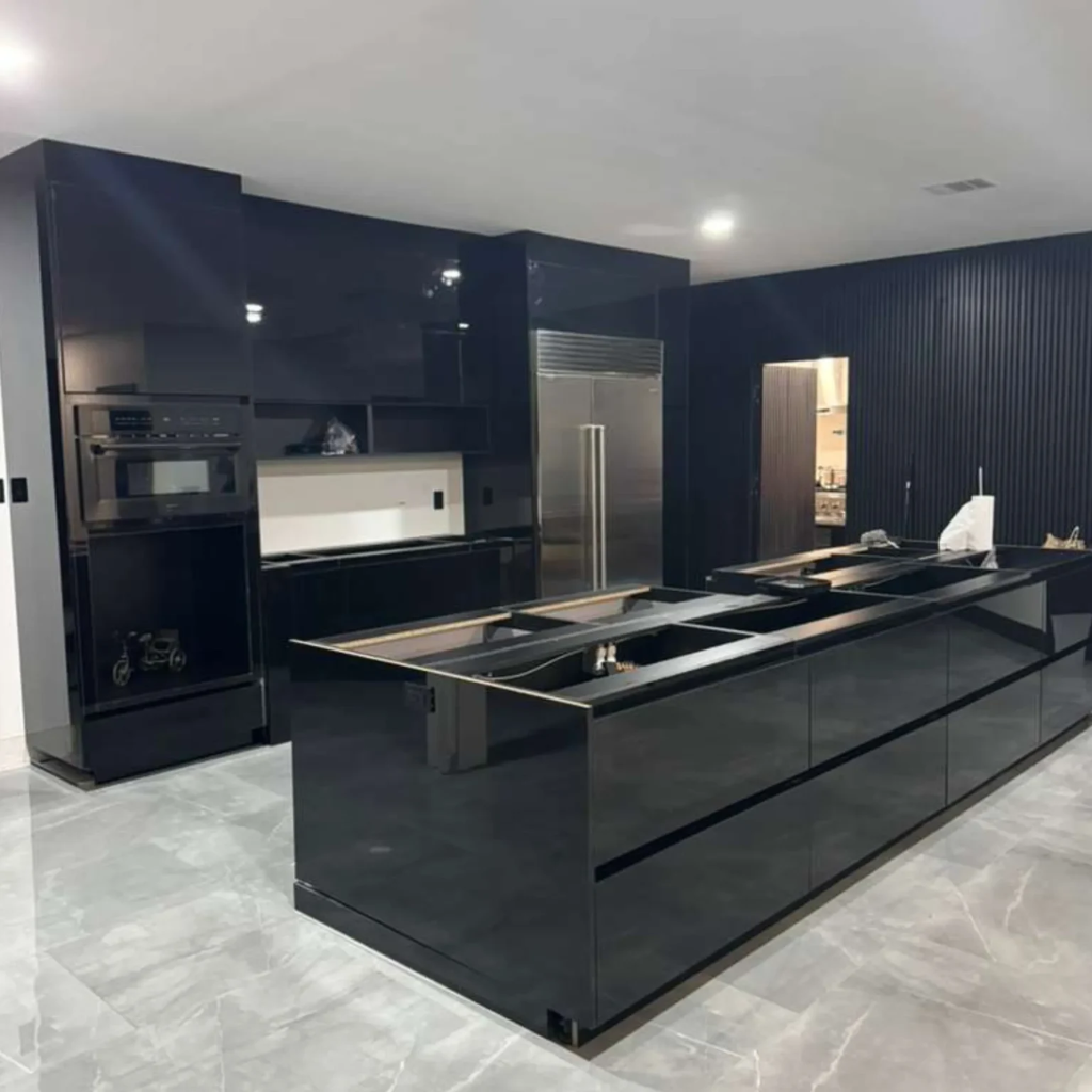 High-gloss black kitchen cabinet installation with oversized island, built-in appliances and porcelain tile flooring in Dallas TX