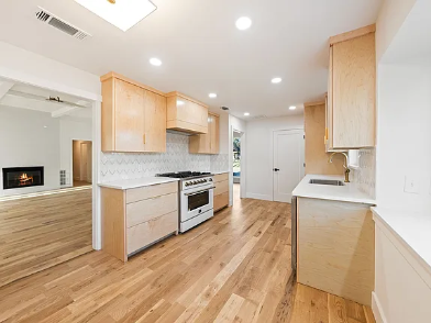 Kitchen renovation with natural wood cabinetry, open shelving, white tile backsplash and professional gas range in DFW Texas