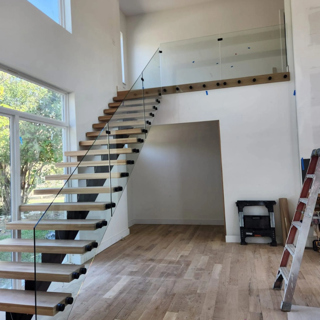 Grand curved luxury staircase with glass railing and marble treads under construction in Dallas Texas by 448 Developments