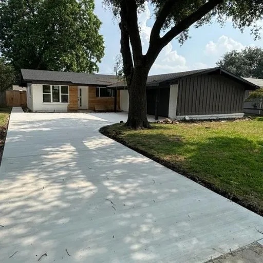 A sleek, smooth concrete driveway installed at a renovated residential property in the Dallas-Fort Worth area, enhancing accessibility and exterior aesthetics.