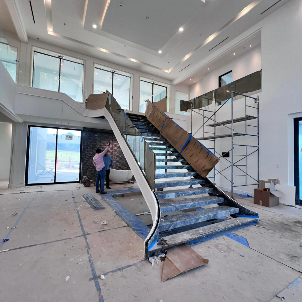 Sleek floating dark wood staircase with black steel stringer and frameless glass railing by 448 Developments in DFW Texas