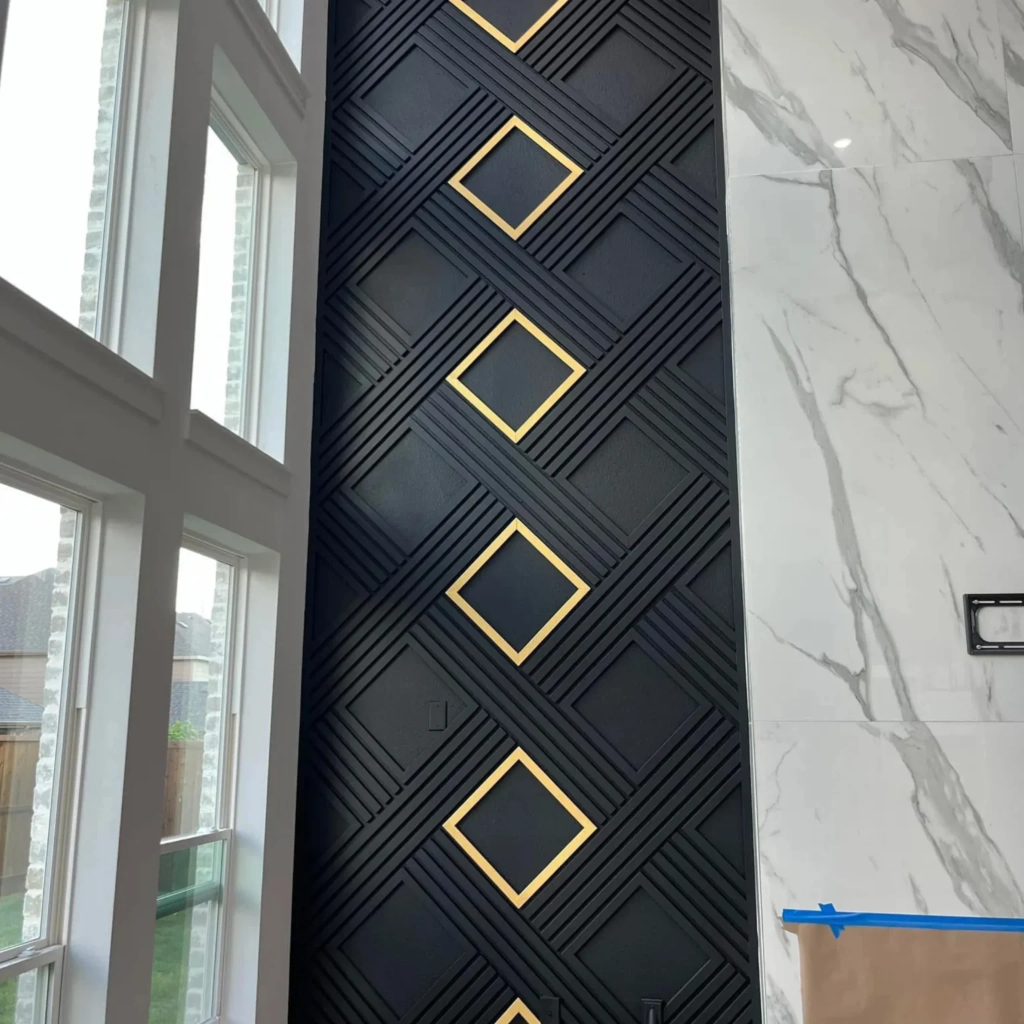 Striking tall accent wall with black geometric paneling and square gold inlays next to large window by 448 Developments Dallas TX