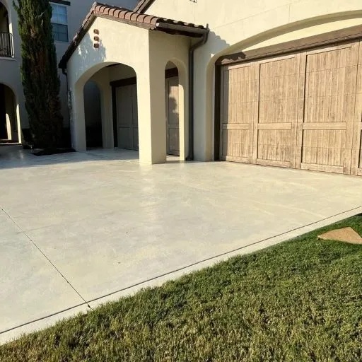 A spacious, clean concrete driveway leading to a multi-car garage entrance at a luxury home in Dallas, featuring durable and elegant concrete surfaces.